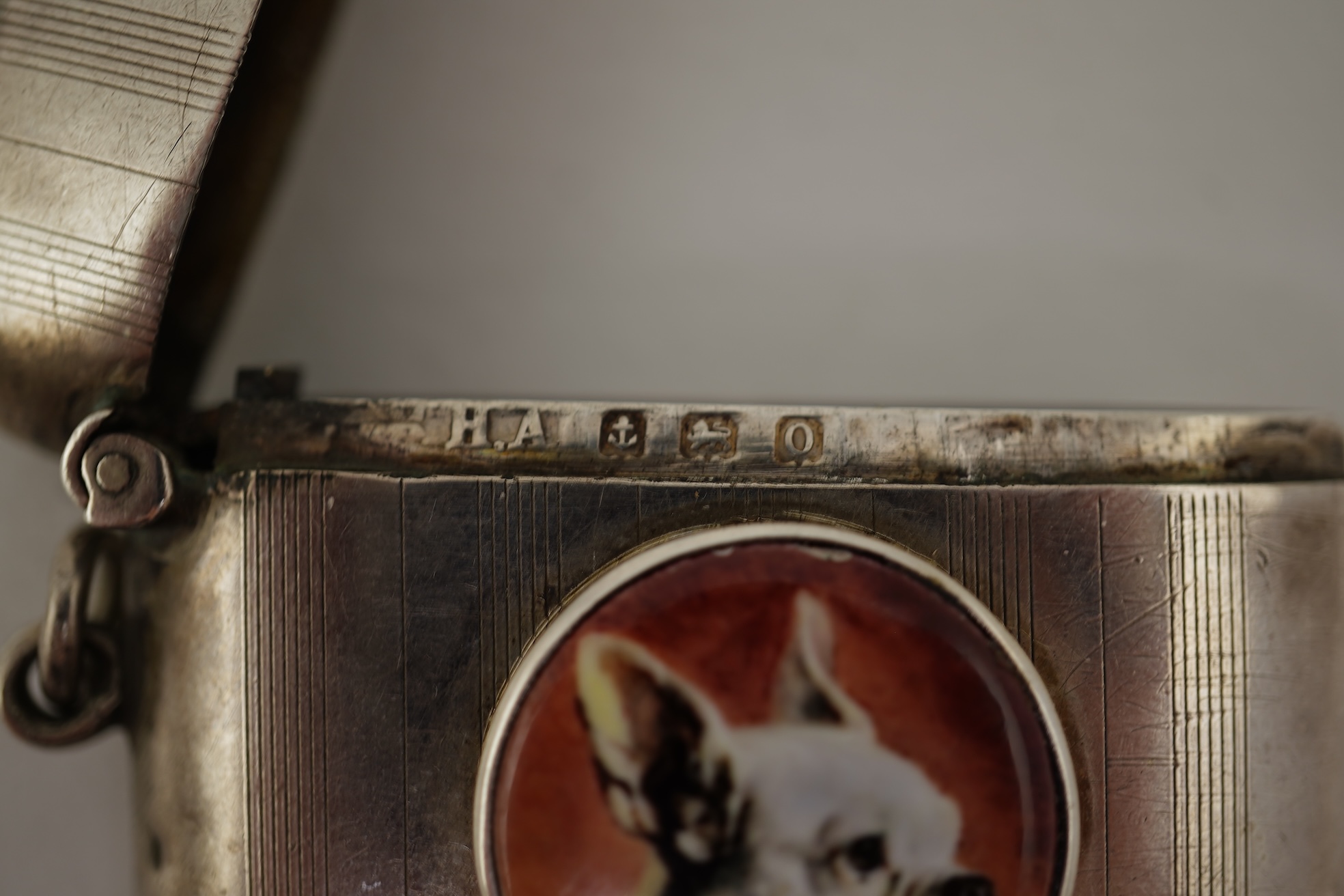 A George V silver and enamel vesta case, by Henry Hyde Aston, the inset circular enamel plaque decorated with a French bulldog